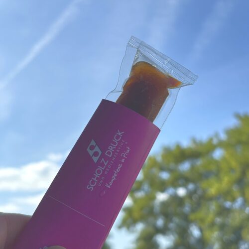 Hand hätl Banderole mit rausguckendem Wassereis Cola in den Himmel - Werbung für Wassereisbanderolen